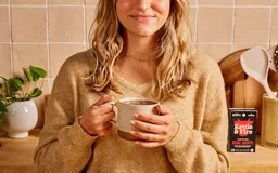 A woman holding a mug of Kettle & Fire bone broth