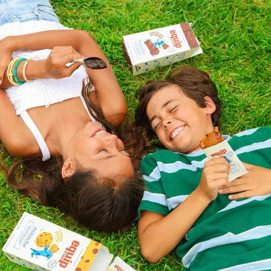 Two kids lying on the grass sharing an Equip Kids bar